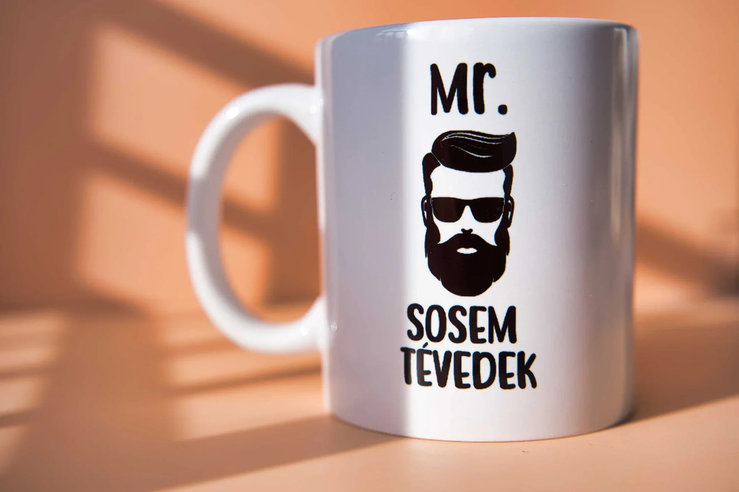 Fehér bögre „Mr. Sosem tévedek” felirattal és szakállas férfi grafikával, napfényben, Zsempiri design ajándék.