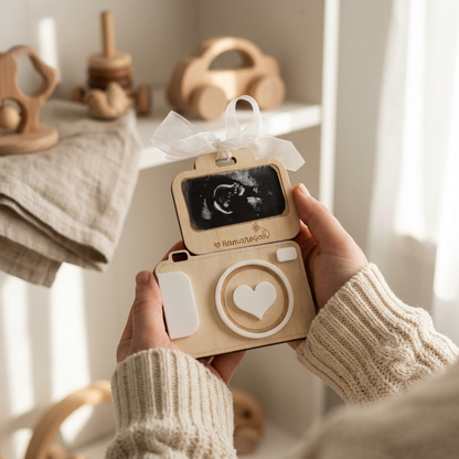Person holding a personalized wooden camera baby announcement with an ultrasound photo.